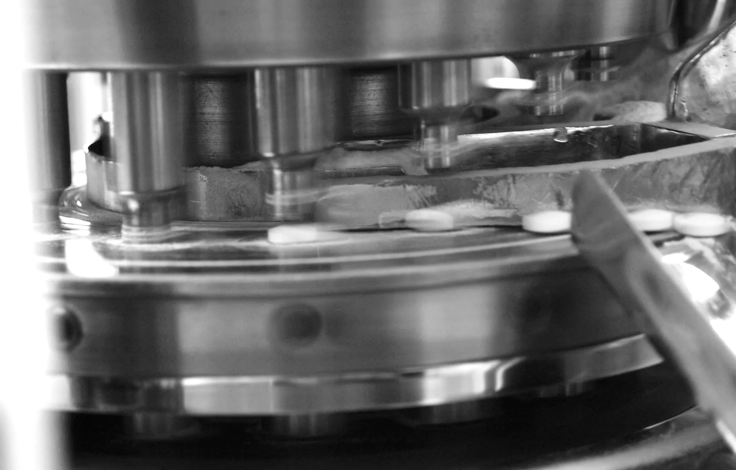 A close up of a rotary tablet press turret featuring the punches.