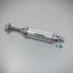 Stokes Tablet Hardness Tester next to a few green tablets.