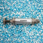 Stokes Tablet Hardness Tester against a bed of white and blue tablets.