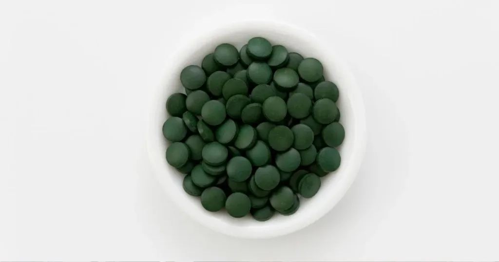 A shot of an upward view of a bowl filled with green round tablets.