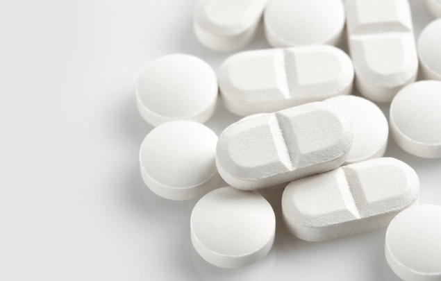 A close up on high quality white round tablets, alongside white bisect caplets.
