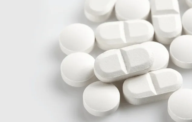A close up on high quality white round tablets, alongside white bisect caplets.