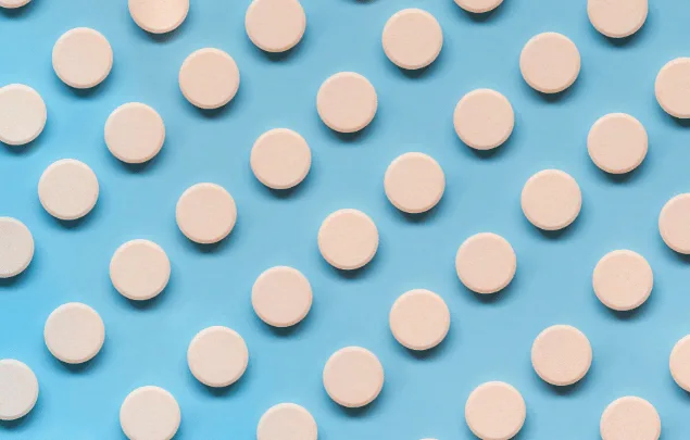 Rows of light tan round effervescent tablets against a blue background.