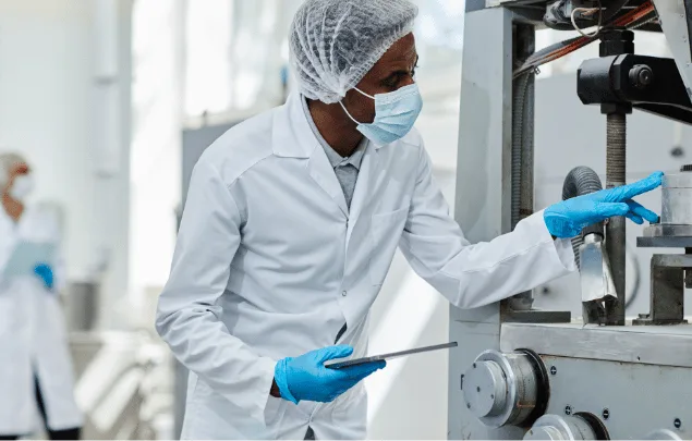 A machine operator performing maintenance on a tablet press.